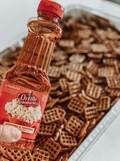 a person holding a bottle of food in front of a tray of waffles