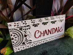 a sign that says chandak on it next to some flowers and plants in the background