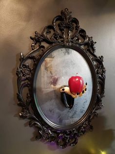 a mirror with an apple sticking out of it's side hanging on the wall