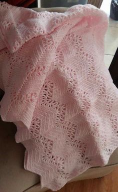 a pink crocheted blanket sitting on top of a couch