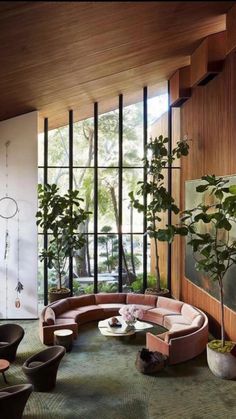 a living room filled with lots of furniture next to tall windows on the side of a wall