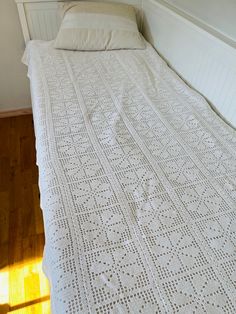 a bed with a white crocheted bedspread on it