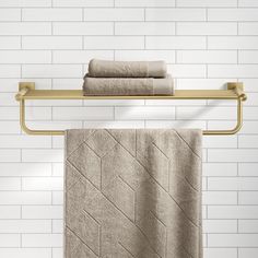 two towels are hanging on a towel rack in front of a white tiled bathroom wall