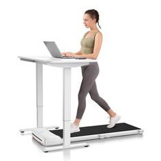 a woman walking on a treadmill while using her laptop