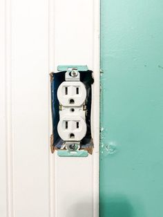 an electrical outlet on the wall in front of a blue and white door