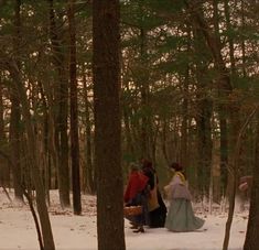 three people walking through the woods in winter clothes and carrying baskets on their backs,