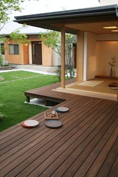 a wooden deck with plates on it and grass in the back ground, next to a house