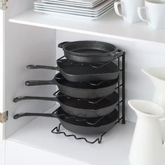 a stack of pots and pans sitting on top of a shelf next to plates