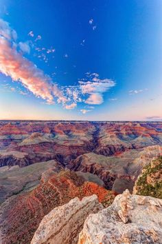 the sun is setting at the edge of the grand canyon, with clouds in the sky