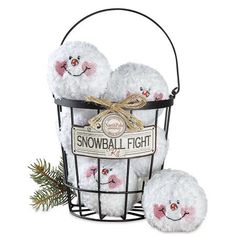 three snowball plush toys in a wire basket with a pine branch on the side