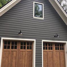 two brown garage doors are open in front of a gray house with white trim and windows