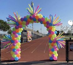 an arch made out of balloons and streamers on the side of a tennis court