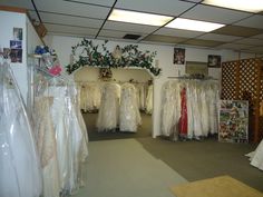 a room filled with lots of white dresses and gowns on display in plastic bags