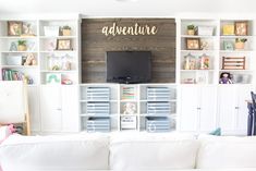 a white couch sitting in front of a tv on top of a wooden wall mounted shelf