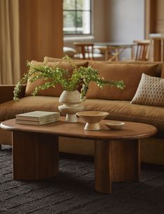 a living room with a couch, coffee table and vase on the end tables in front of it