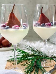 two wine glasses filled with dessert and garnished with pears on a cutting board