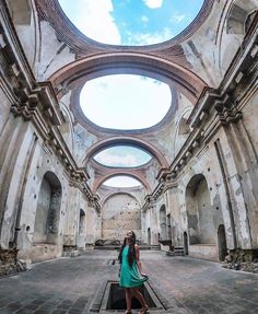 a woman standing in an old building with a skylight above her and the floor is tiled