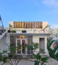 a small white house with plants growing out of it's windows and doors on the roof