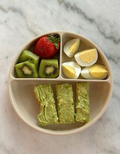 an assortment of fruits and veggies in a bowl on a marble counter top