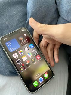 a person holding an iphone in their hand with icons on the screen and other app icons