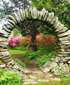 a stone arch in the middle of a garden