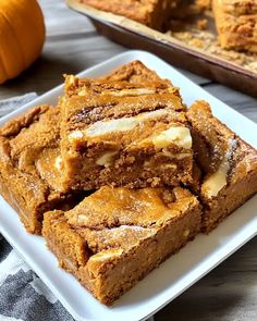 some brownies are on a white plate with pumpkins in the background