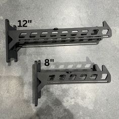 two black metal brackets are on the floor next to each other with measurements for them