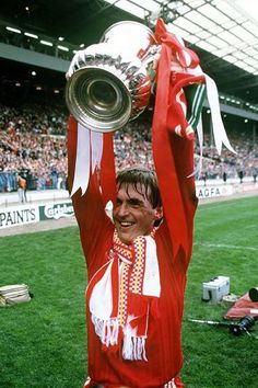 a man holding up a trophy on top of a field