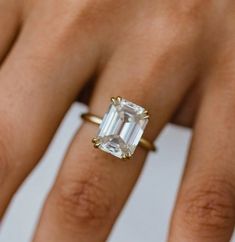 a woman's hand with a ring on it and an emerald stone in the middle