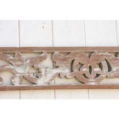 an old wooden sign is hanging on the side of a white building with peeling paint