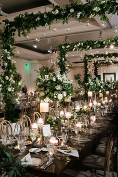 a long table is set with candles, flowers and greenery for an elegant wedding reception