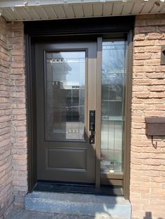 the front door to a brick building with a glass paneled door and sidelight