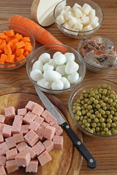 there are many different types of food in bowls on the table, including meats and vegetables