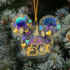 a mickey mouse ornament hanging from a christmas tree with disney's castle in the background