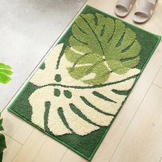 a green and white rug on the floor next to some shoes, plant and potted plants