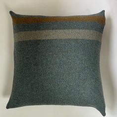 a green and brown striped pillow sitting on top of a white wall