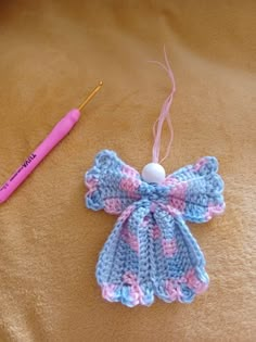 a crocheted angel ornament next to a knitting needle