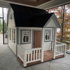 a small house with a porch and deck in the middle of an open patio area