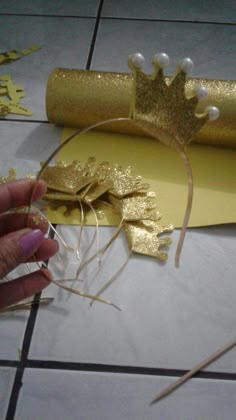 someone is cutting out some gold paper with scissors and thread on the table next to it