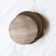 three metal discs sitting on top of a white marble counter