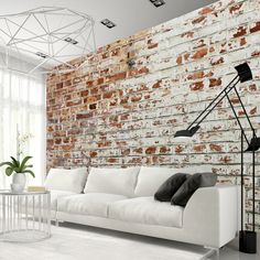 a white couch sitting in front of a brick wall next to a table with a lamp on it