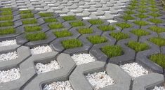 grass growing out of cement blocks in the middle of a walkway with rocks and gravel