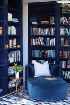 a living room filled with blue bookshelves and a round chair next to a coffee table