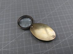 an antique looking metal object with a magnifying glass on it's side