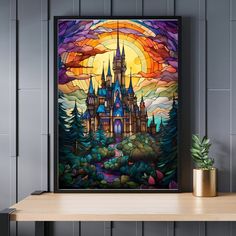 a stained glass window with a castle in the background on a shelf next to a potted plant