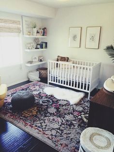 a baby's room with a crib, rug and pictures on the wall