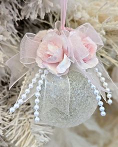 a christmas ornament hanging from the side of a tree with flowers on it