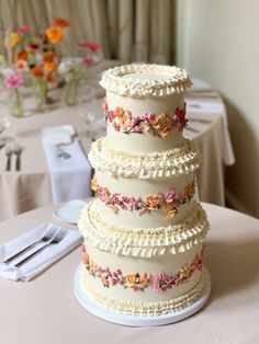 a wedding cake sitting on top of a table next to a white table cloth covered table