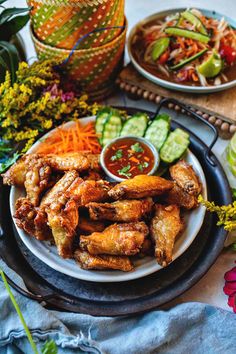 two plates with chicken wings and vegetables on them