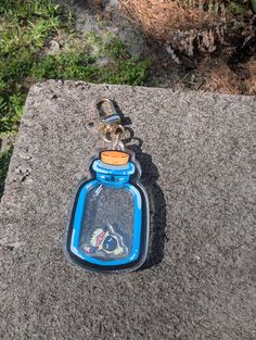 a blue glass bottle with a key chain attached to it sitting on a rock in the grass